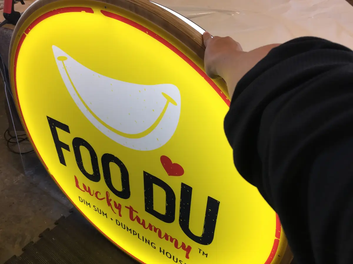 Circular illuminated Foo Du brand sign.