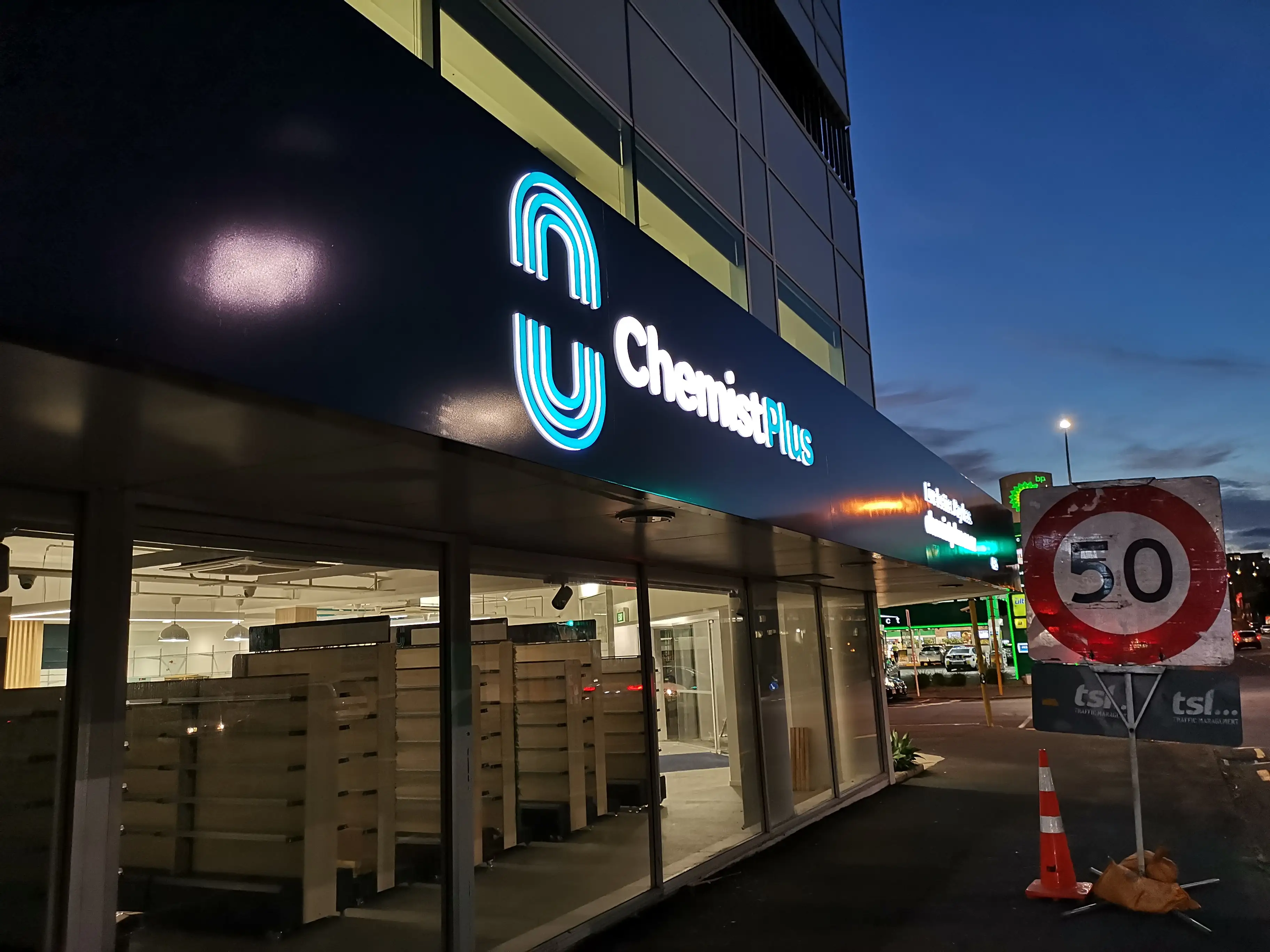 Illuminated pharmacy identity at the shopfront.