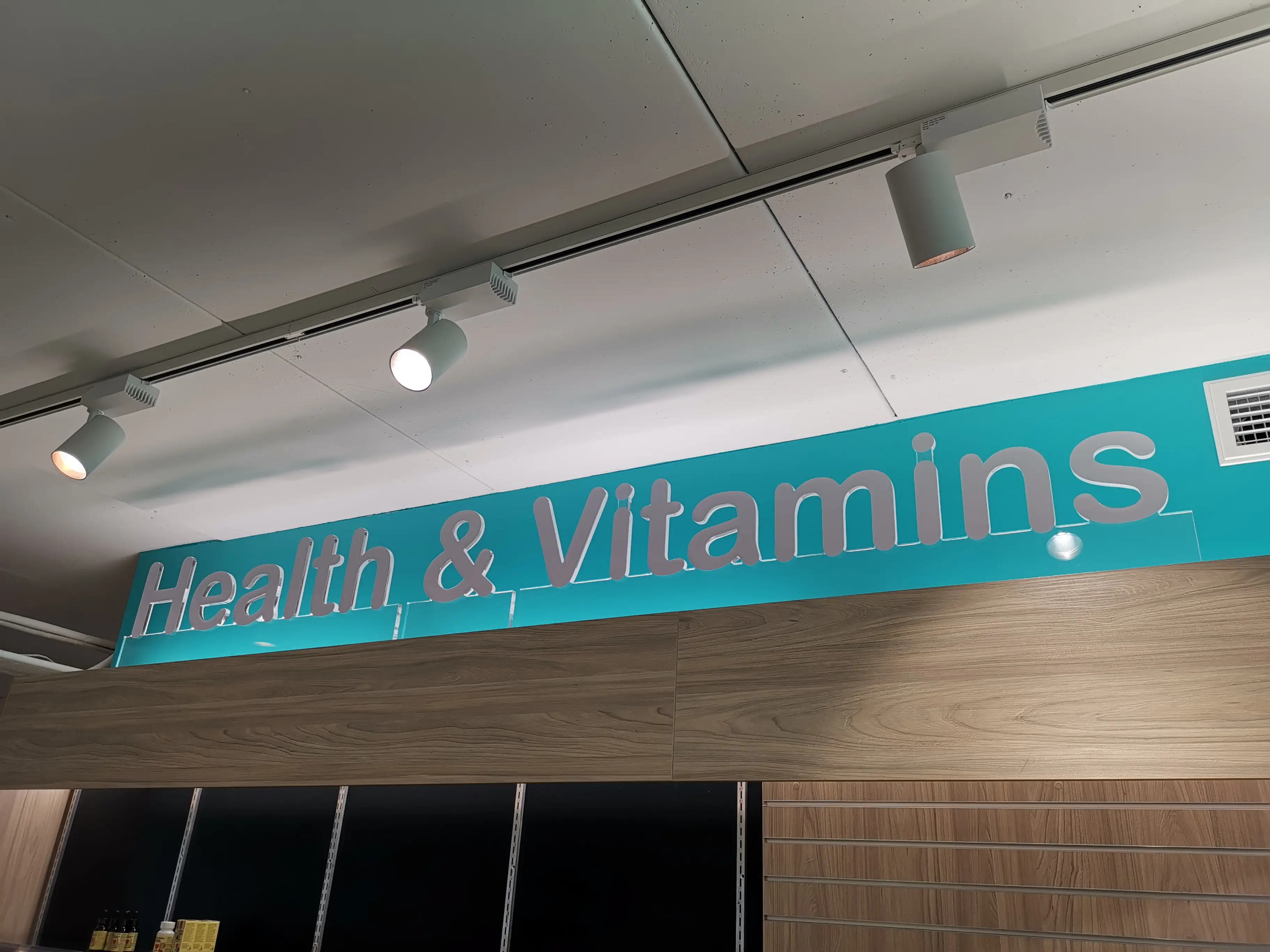 Chemist Plus retail interior with overhead brand signage.