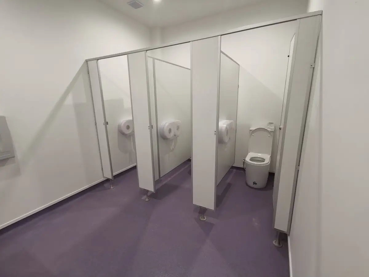White toilet cubicle partitions above purple washroom flooring.