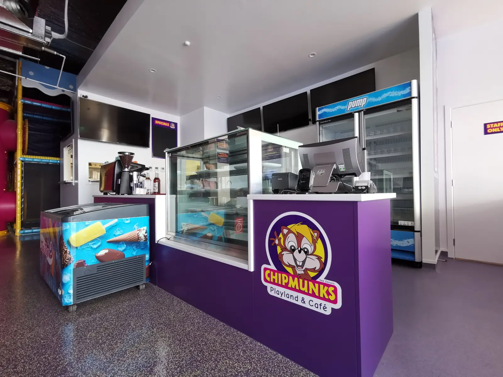 Branded café counter with a glass display cabinet, coffee equipment and drinks refrigeration.