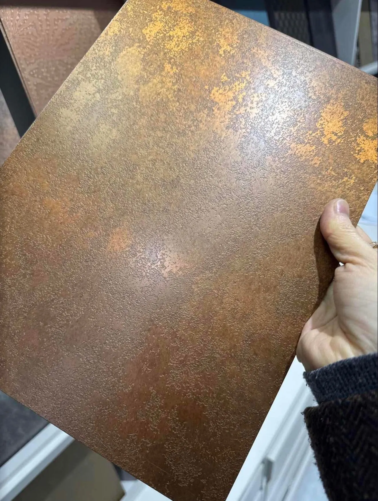 Close view of a warm aged-bronze architectural metal finish sample