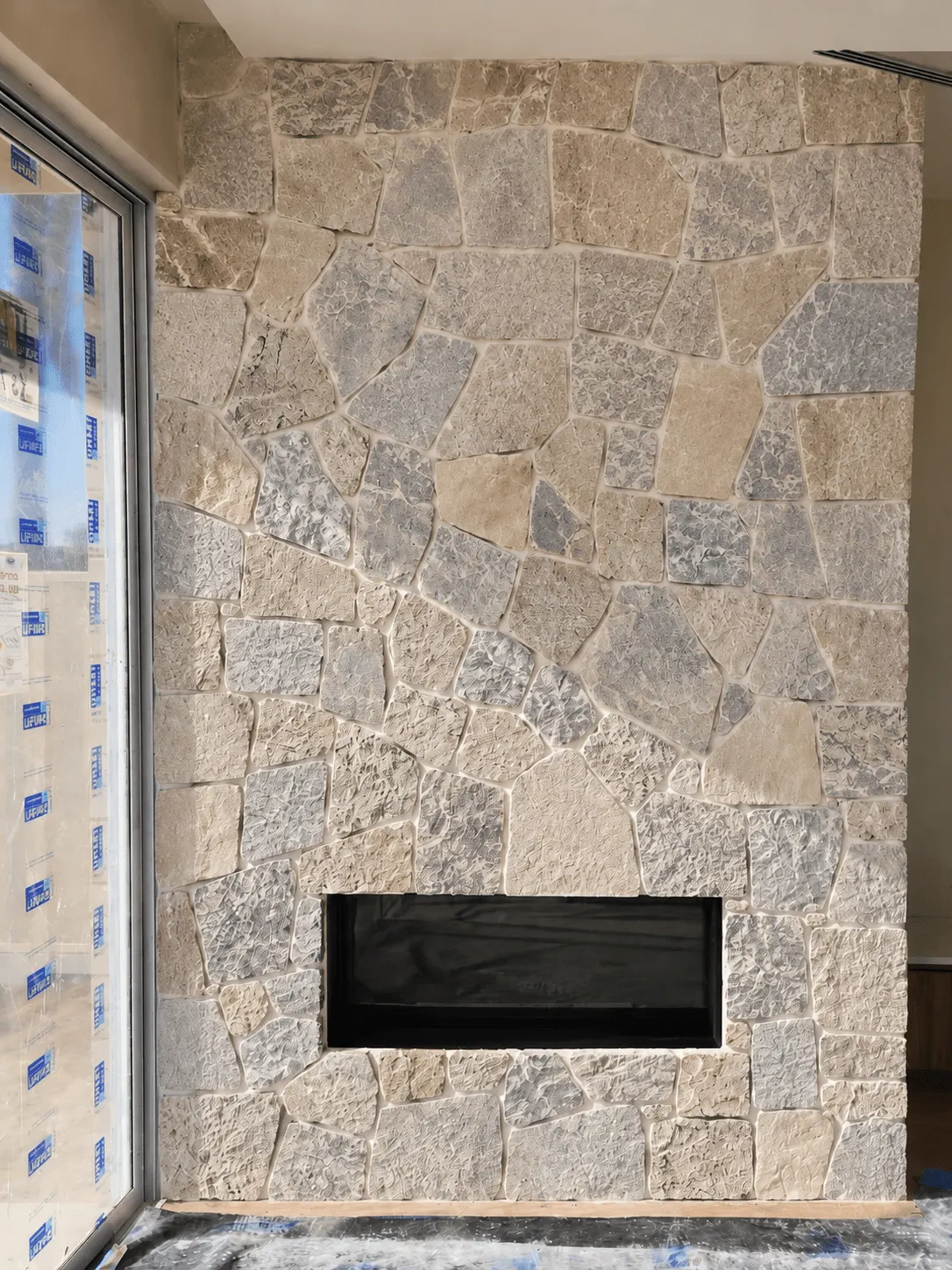 Pale ashlar-style stone wall finish installed around a recessed fireplace