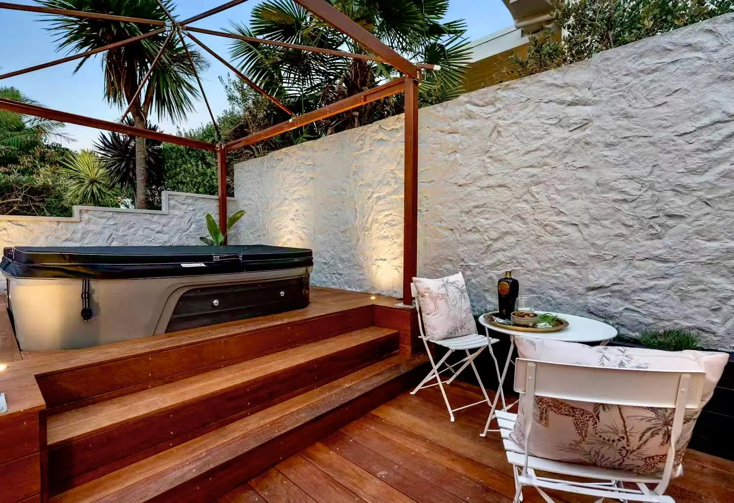 Supplier reference showing a white textured rock wall beside an outdoor spa and timber deck