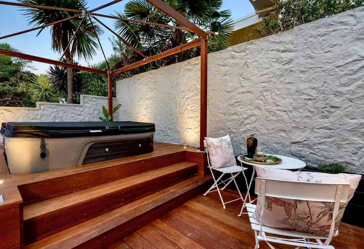 Supplier reference showing a white textured rock wall beside an outdoor spa and timber deck